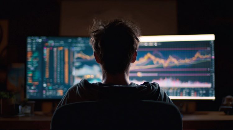A person thoughtfully analyzing a financial projection on a screen, with growth charts and data points.